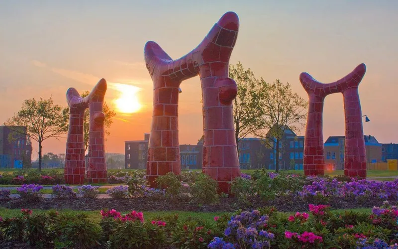 De rode kunstwerken van het Keipark tussen bloemen bij zonsondergang